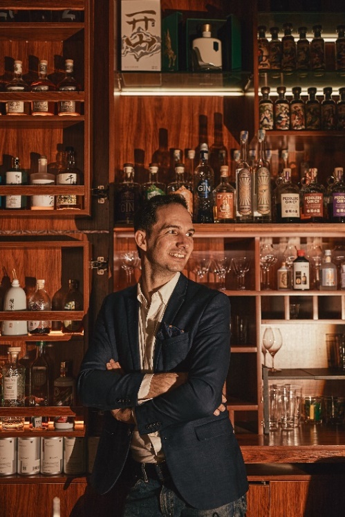 A person standing in front of a bar Description automatically generated