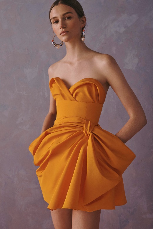 A person wearing an orange dress Description automatically generated
