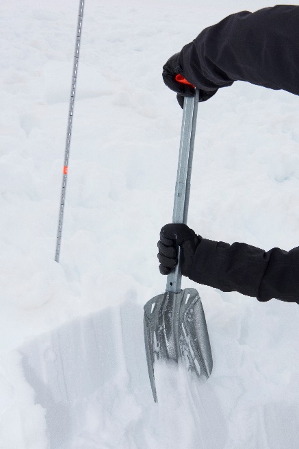 A person shoveling snow in the snow Description automatically generated